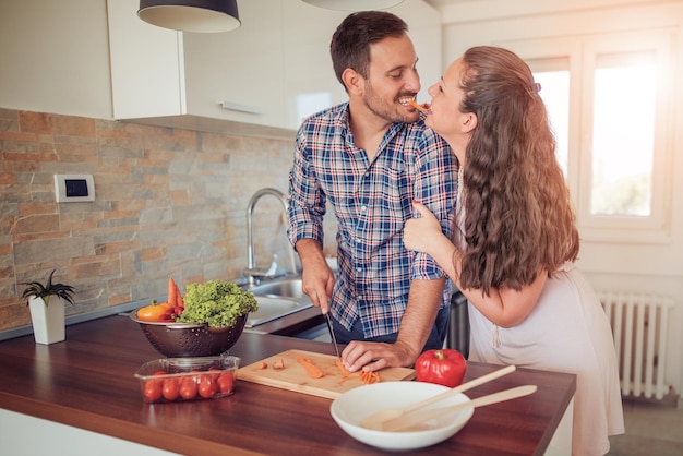 Het gelukkige jonge paar heeft pret in moderne keuken