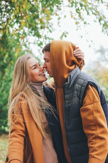 Het gelukkige jonge paar in de vrienden van liefdetieners kleedde zich in het toevallige stijl kussen op stadsstraat in koud seizoen