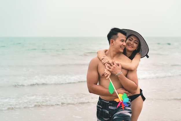 Het gelukkige jonge paar in liefde omhelst en hebbend pret op tropisch strand in de zomervakantie