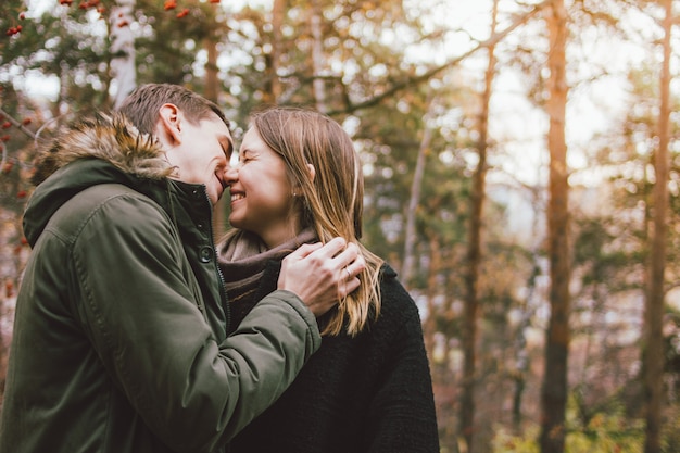 Het gelukkige jonge paar in liefdevrienden kleedde zich in het toevallige stijl kussen in het bos van het aardpark in koud seizoen, de reis van familieavvenure