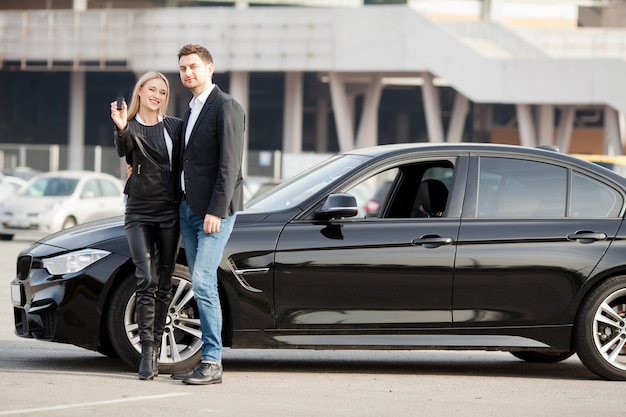 Het gelukkige jonge paar kiest en koopt een nieuwe auto voor het gezin.