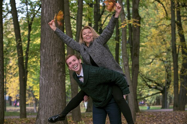 Het gelukkige jonge paar spelen met gevallen bladeren in de herfstpark