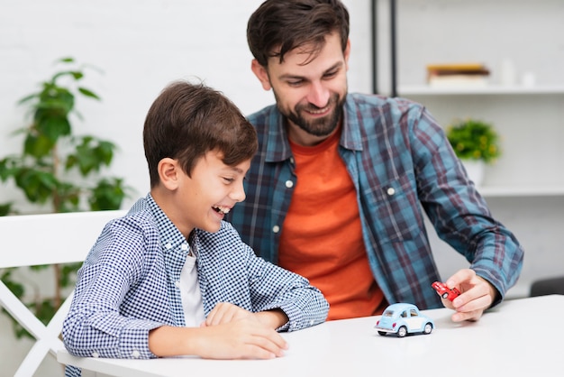 Het gelukkige jongen spelen met stuk speelgoed auto's met zijn papa