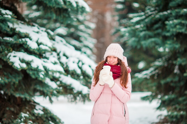 Het gelukkige meisje geniet in openlucht van de winter en sneeuwweer op mooie winnterdag