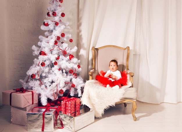 Het gelukkige meisje van het babykind dichtbij een Kerstboom