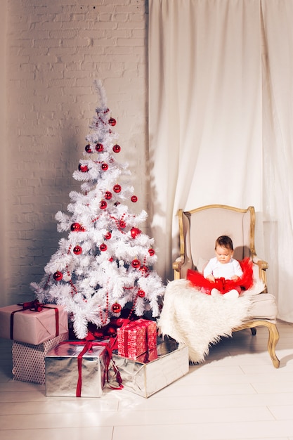 Het gelukkige meisje van het babykind dichtbij een Kerstboom