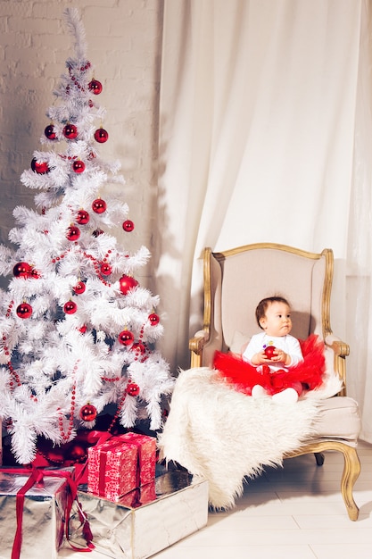 Het gelukkige meisje van het babykind dichtbij een Kerstboom