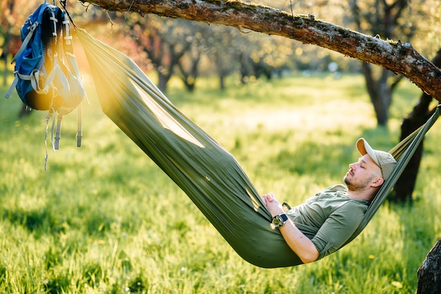 Foto het gelukkige mens ontspannen in hangmat het hangen op appelboom in de zomer zonnig park.