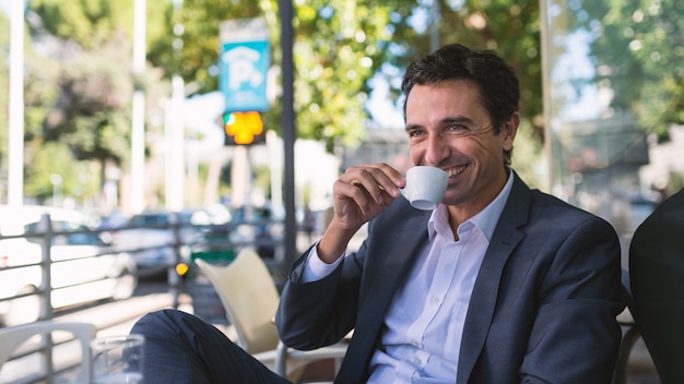 Het gelukkige portret dat van de middenleeftijdszakenman een koffie in openlucht in Rome, Italië drinkt.