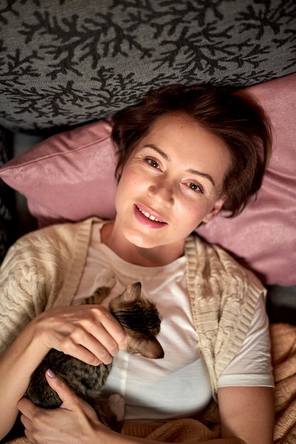 Het gelukkige vrouw spelen met de kat in de slaapkamer