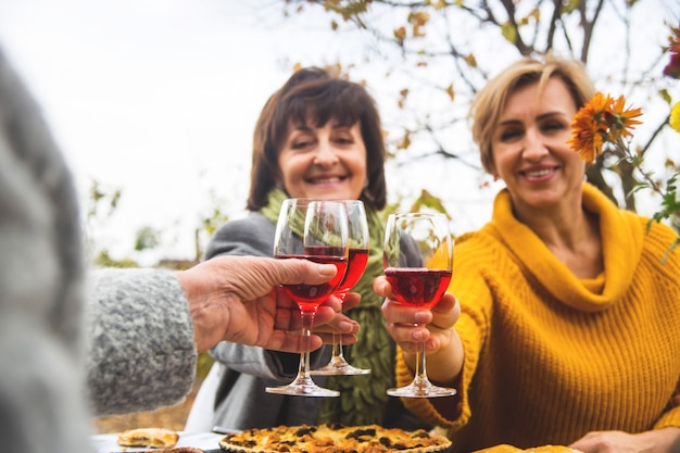 Het gerinkelglazen van vrouwen met wijn bij het diner van de de herfstfamilie.