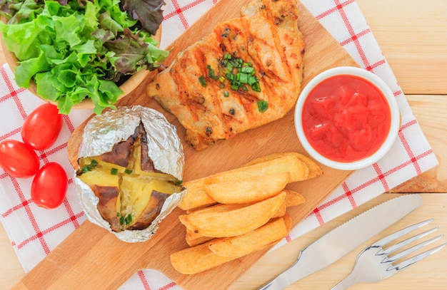 Het geroosterde vleeslapje vlees dient met tomatensaus en plantaardige salade op houten achtergrond