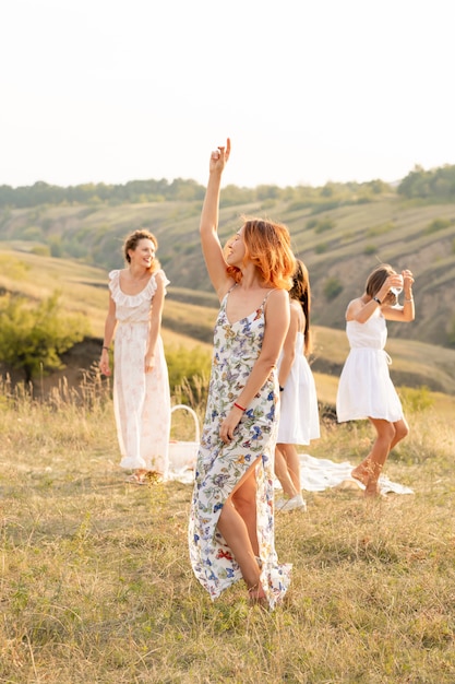 Het gezelschap van gelukkige vriendinnen die plezier hebben en buiten dansen op een picknick in de heuvels.