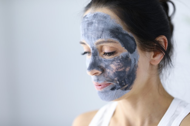 Het gezicht van de vrouw is bedekt met een cosmetisch masker van klei voor huidverjonging