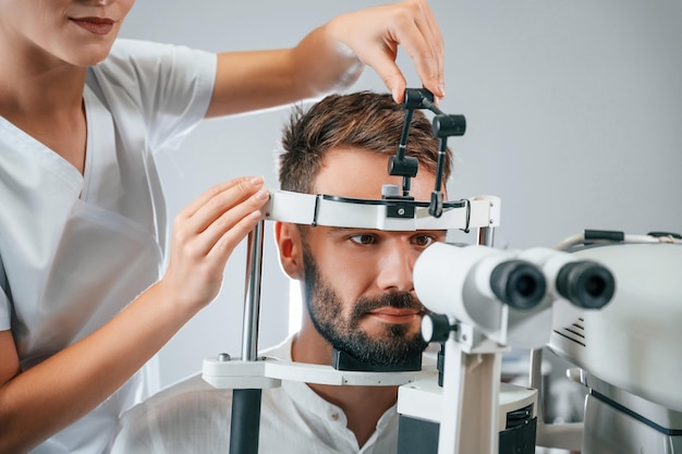 Het gezichtsvermogen van de mens gecontroleerd door een vrouwelijke arts in de kliniek met behulp van een speciaal optometristenapparaat