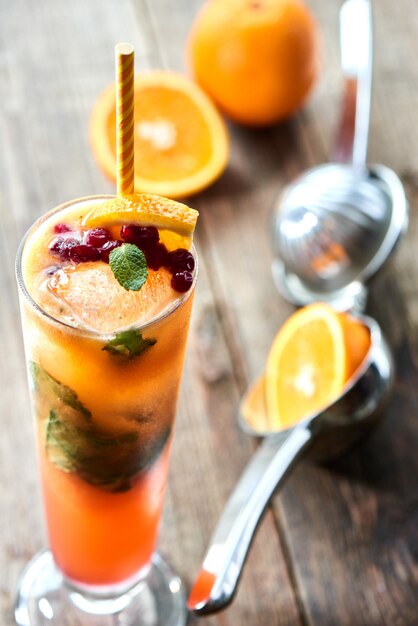 Het glas alcoholische cocktail seks op het strand zelfgemaakte cranberry, mint, sinaasappel en perzik sap op een houten tafel close-up