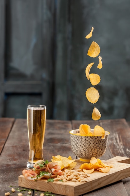 Het glas bier en chips, pistachenoten geïsoleerd op een witte