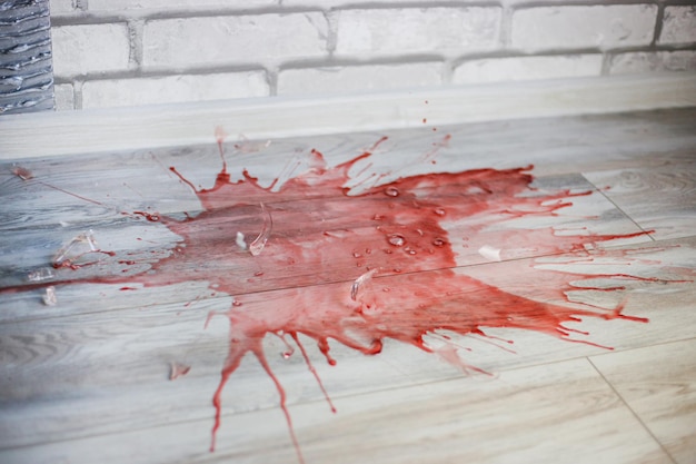 Foto het glas breekt op de grond, glasscherven vliegen in het rond en rode wijn morst.