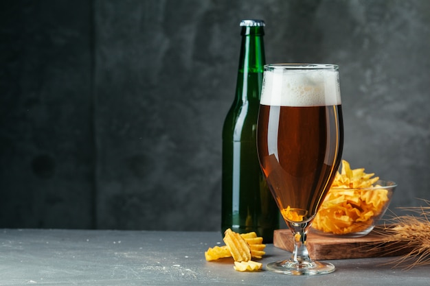 Het glas donker bier met kom biersnacks sluit omhoog