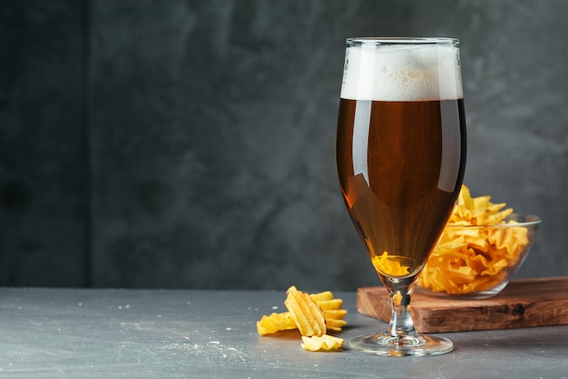 Het glas donker bier met kom biersnacks sluit omhoog