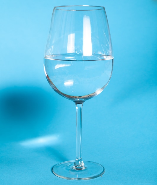 Foto het glas is half gevuld met water. een glas water staat op een blauwe muur gezond voedselconcept healthy