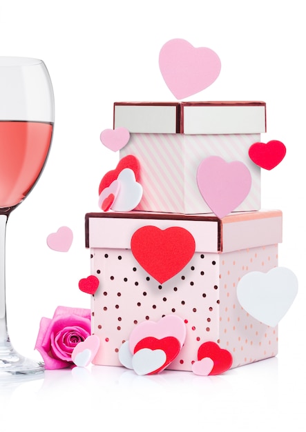 Het glas roze wijn met hart en roze giftdoos en nam voor Valentijnsdag op witte achtergrond met vliegend hart toe