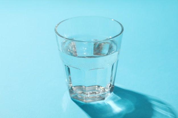 Het glas water op blauw, sluit omhoog