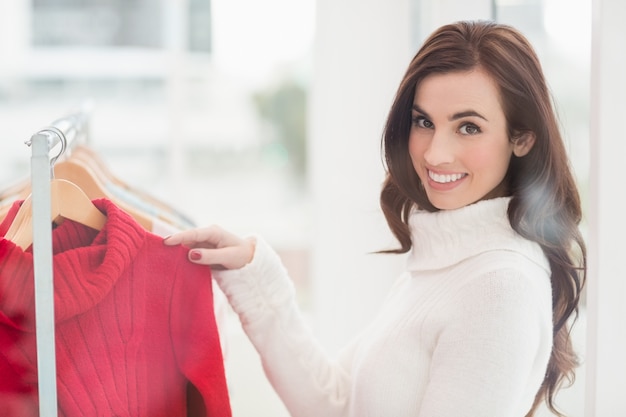 Het glimlachen brunette die kleren op spoor bekijken