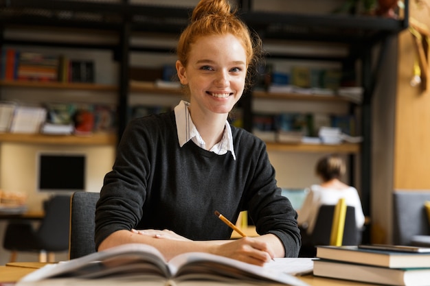 Foto het glimlachen het roodharige tienermeisje studeren