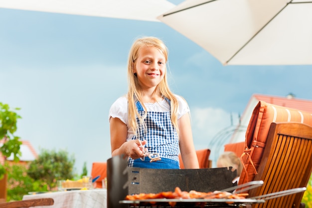 Foto het glimlachen meisje het stellen met de barbecuegrill