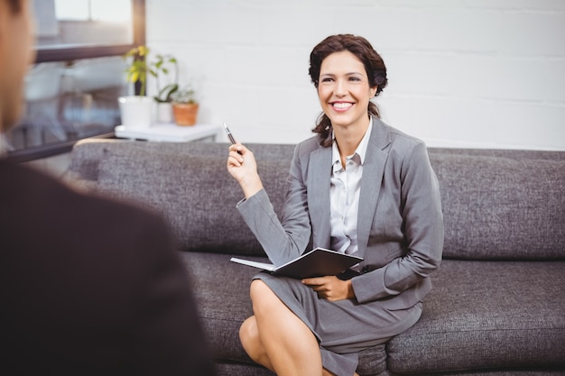 Het glimlachen onderneemsterzitting op bank in bureau