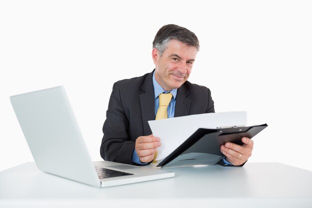 Het glimlachen van de documenten van de mensenlezing op zijn bureau