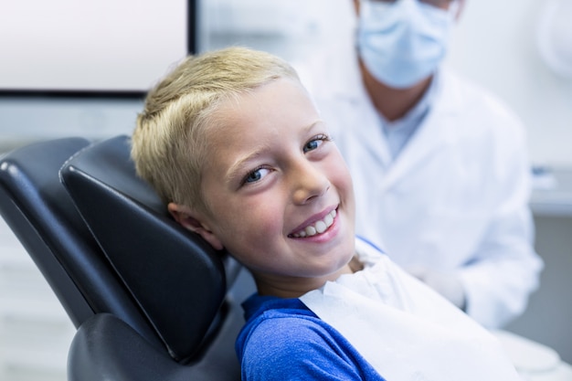 Het glimlachen van jonge geduldige zitting op tandartsstoel