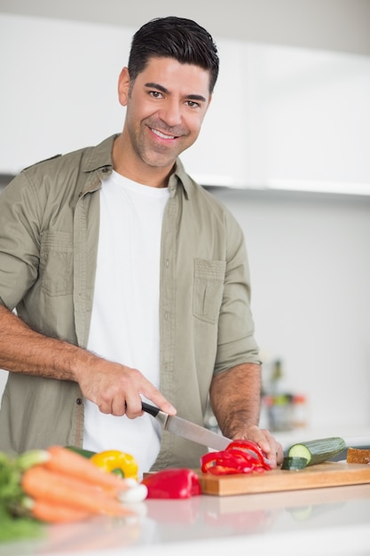 Het glimlachen van mensen hakkende groenten in keuken