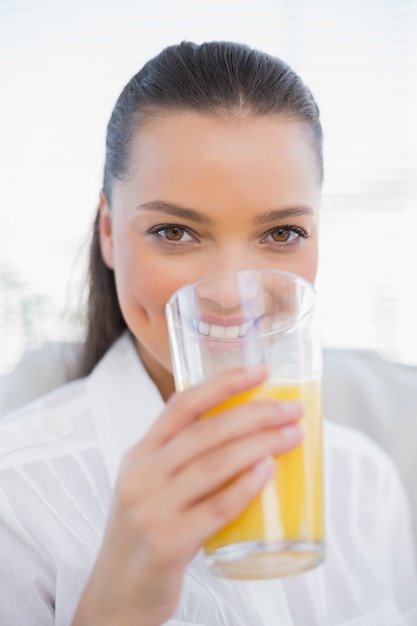 Het glimlachen van mooie vrouw het drinken jus d&#39;orangezitting op comfortabele laag