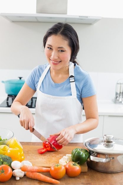 Het glimlachen van vrouwen hakkende groenten in keuken