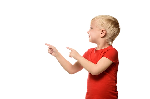 Het glimlachen van weinig blonde jongen in een rood overhemd bevindt zich en toont wijsvingers aan kant.