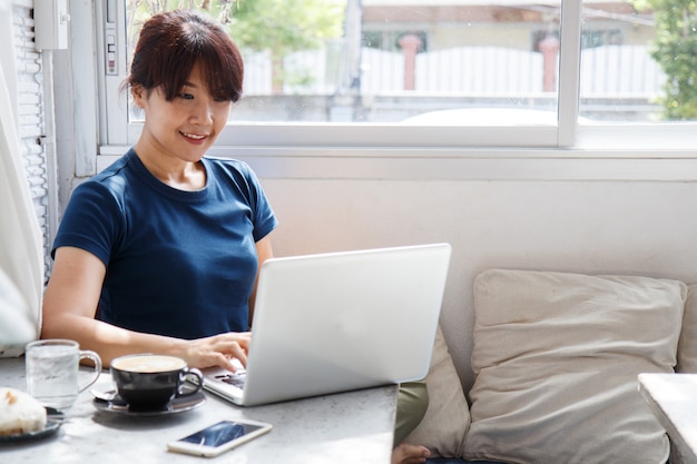 Het glimlachen vrouw het letten op video op laptop computer in comfortabel mede werkend binnenland,