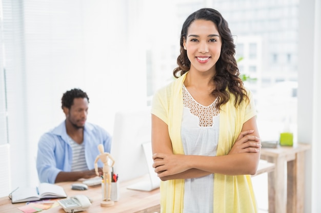 Het glimlachen vrouw het stellen voor haar collega met gekruiste wapens