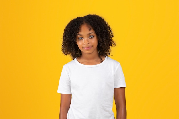 Het glimlachende adolescente Afrikaanse Amerikaanse meisje in witte t-shirt bekijkt camera