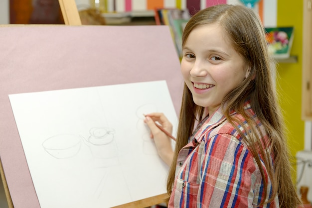 Het glimlachende jonge kunstenaarsmeisje trekt