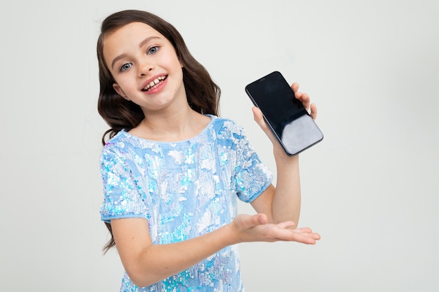 Het glimlachende meisje toont het lege telefoonscherm met een model op een studio
