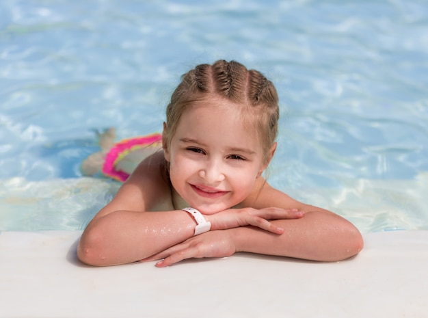 Het glimlachende meisje zwemt naar het zwembad