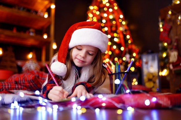 Het grappige meisje in Kerstmanhoed schrijft brief aan Kerstman