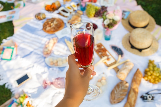 Het greepglas van de vrouwengreep met rode champagne bij picknick