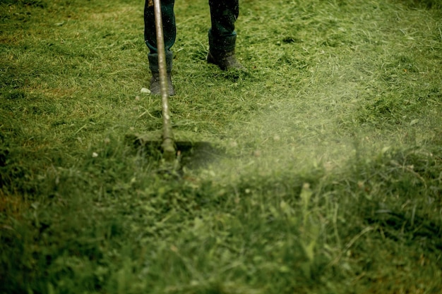 Het hoofd van een handmatige grasmaaier op benzine terwijl u werkt tegen de achtergrond van vers gemaaid gras