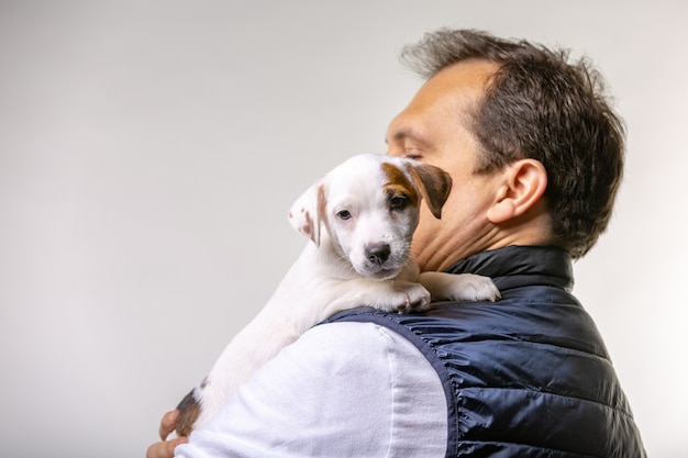 Het horizontale portret van de knappe vrolijke mens houdt jack russell terrirer, heeft blije uitdrukking