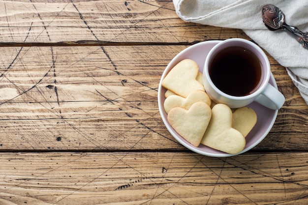 Het huiskoekjes van het hart en kop van koffie op een plaat