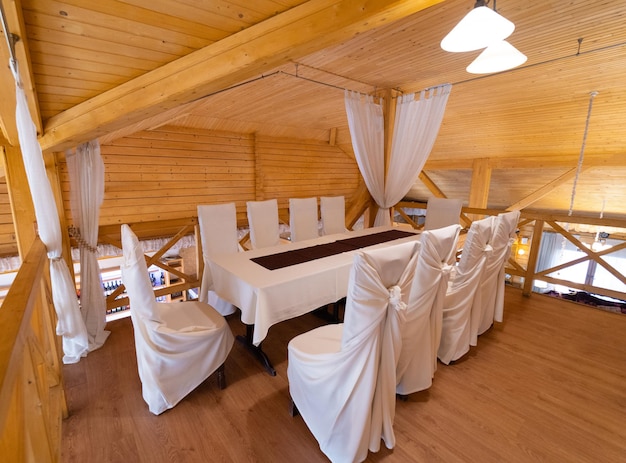 Het interieur van het restaurant in de stijl van hout met een grote tafel en stoelen