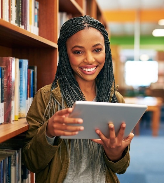 Het is alsof ik honderden boeken in mijn handen heb Portret van een universiteitsstudent die een digitale tablet gebruikt in de bibliotheek op de campus